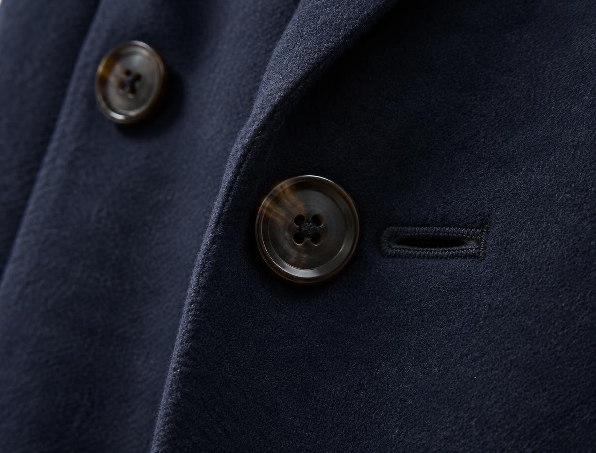 Close-up of dark horn buttons and a bound buttonhole on a navy wool overcoat