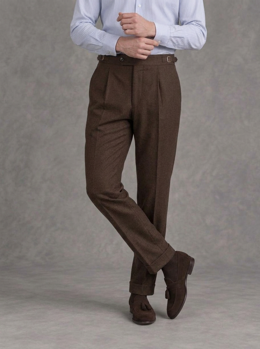 Chocolate brown single-pleat flannel trousers with side adjusters and turn-ups, worn with a striped blue shirt and brown suede tassel loafers