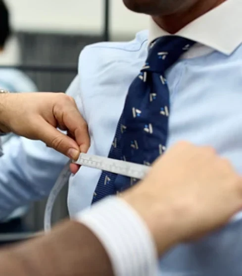 Tailor measuring a client's chest with a white measuring tape
